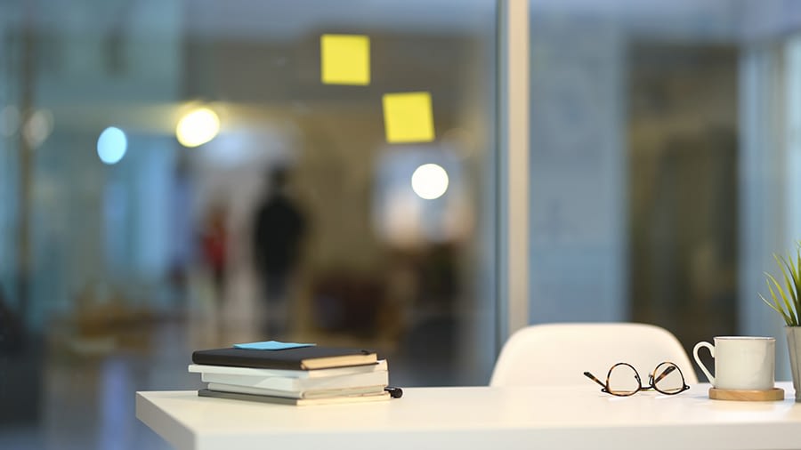 A desk with glasses and a books on the surface
