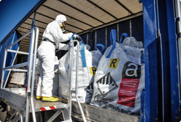A worker in a hazmat suit handling asbestos