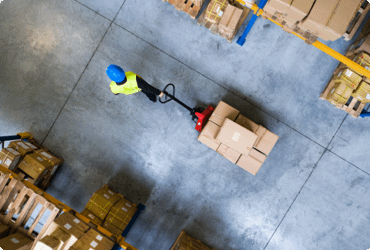 An employee safely moves a pallet with a manual hydraulic forklift