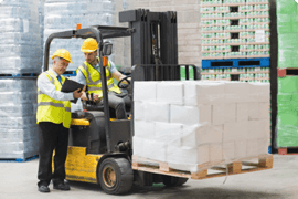 Two men and a forklift carrying a load of concrete blocks