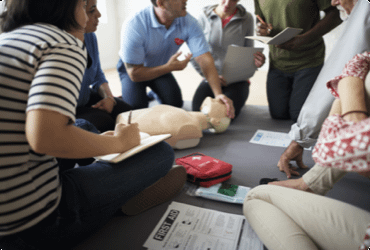 Employees take notes as they are instructed on how to perform first aid and CPR