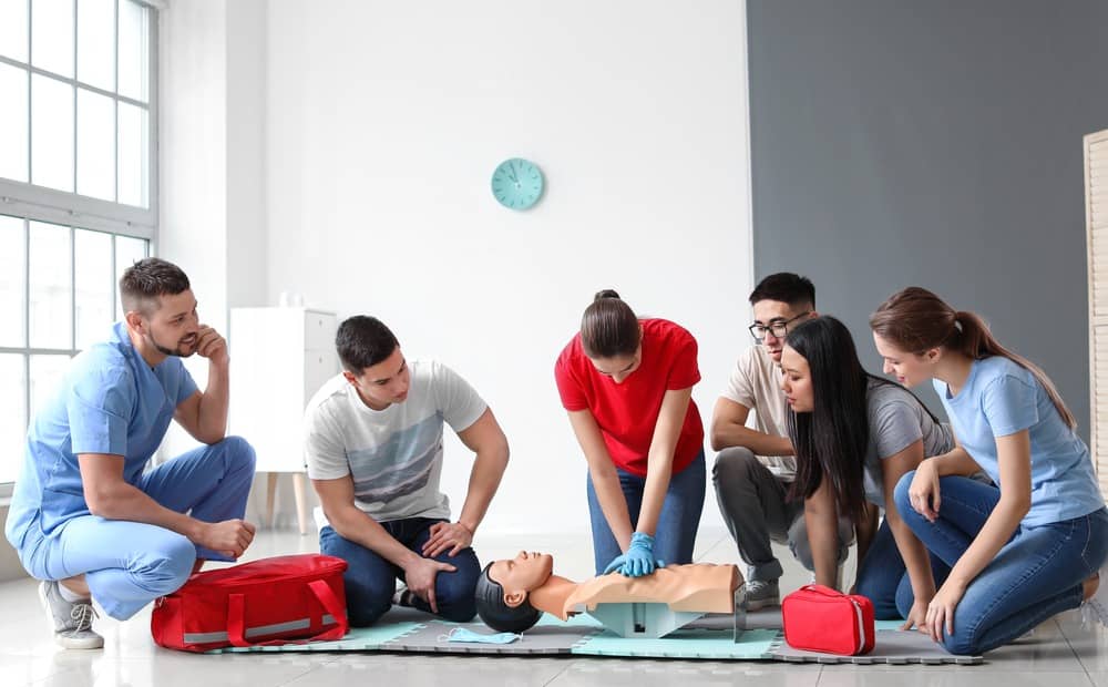 Group of five people and instructor performing CPR in first aid and CPR training