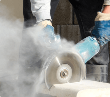 A worker uses a circular saw to cut through concrete