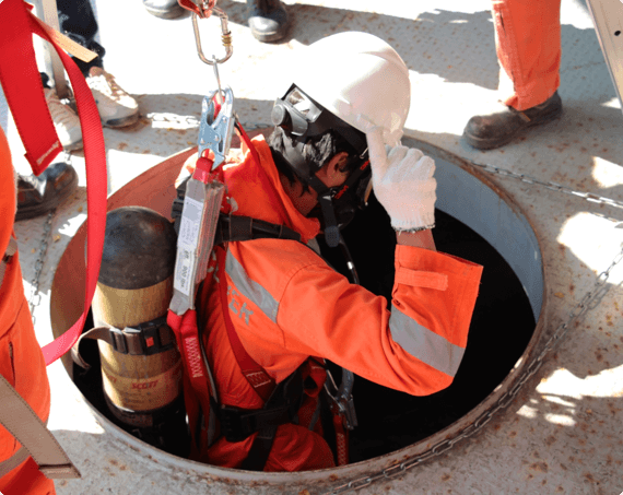 a worker with a harness is lowered into a confined space