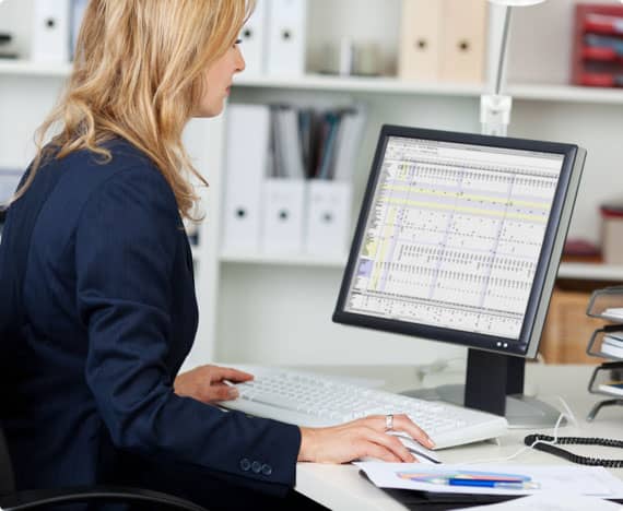 An employee works on a spreadsheet seated at an ergonomic desk